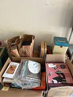 Boxes and bags containing various vintage photo albums, books, and record albums stacked together on a surface.