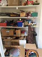Shelf and floor view showing boxes with assorted miscellaneous items, a pinecone Christmas tree, and various containers holding hardware and tools.