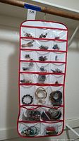 Full view of hanging organizer with multiple clear pockets filled with assorted jewelry.