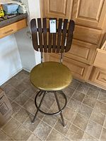 Front view of the mid-century kitchen stool with vinyl seat, wooden backrest, and metal frame with footrest.
