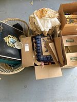 Box containing folded lace and crocheted doilies and table linens, and a wicker basket underneath holding more items