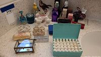 Overview of the collection showing vintage lipstick holders, glass perfume bottles, bird figurines, letter stamps, and small decorative items.
