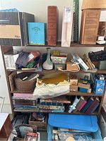 Full view of wooden shelf loaded with assorted photo albums, boxes, and party supplies.