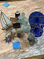 Photo showing all 13 pieces including frosted glass Inukshuks, stained glass flowers, blue glass discs, sailboat, floral glass piece, ducks/snails, vintage paperweights, Pepsi can for scale