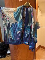 Multicolored silk jacket hanging on hanger, front view showing abstract floral pattern in blues, reds, whites, pinks and corals