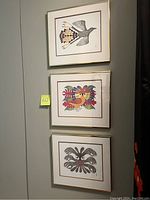Three framed prints hung vertically on wall