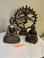 Front view of the three statues grouped together on a white textured cloth giving clear view of each figure and their details.
