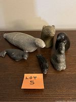 Top view showing six stone animal sculptures on a wooden surface with Lot 5 label