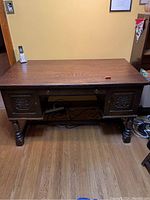 Front view of the solid oak desk showing two carved side doors and main drawer
