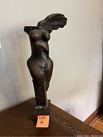 Frontal view of abstract winged female sculpture on wood surface