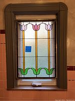 Full view of stained glass panel installed in window, showing three tulip design.
