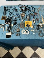 Overview of mixed vintage estate jewelry laid on blue fabric, showing various necklaces, earrings, bracelets, and rings including pieces stamped Kate Porter.