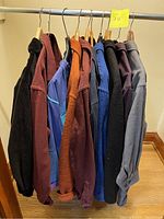 Lot of various flannel and corduroy shirts and jackets hung on a rack, showing colors and textures.
