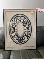 Front view of framed print leaning on couch, hand holding upper right corner