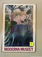 Framed vintage print labeled Moderna Museet featuring a colorful stylized landscape with trees and plants, showing waviness under glass.