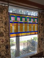 Panel hung in window during daylight, showing overall design and color vibrancy.