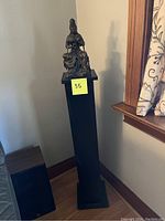 Full view of statue and painted wood plinth in room corner