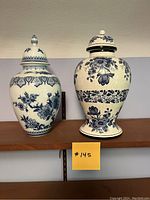 Pair of two blue and white ginger jars, large on left and smaller on right, on display shelf.