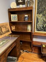 The bookcase shown with visiting decorative items and furniture around it to depict scale and condition.