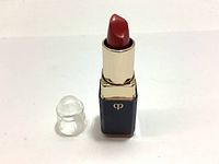 Opened Cle De Peau lip product showing reddish-brown lipstick bullet with transparent plastic cap removed and placed beside it.