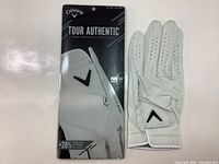 Photo of packaged and unpackaged white Callaway Tour Authentic Cabretta leather golf glove, showing front and back sides, highlighting product branding and material.