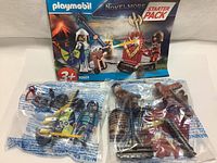 Photo showing all Playmobil toys sealed in original plastic bags with instruction sheet in the background.