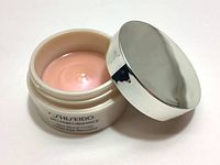 Open jar showing the pale pink cream inside with silver lid placed beside it.