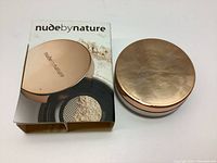 Photo of Nude by Nature loose finishing powder container with rose gold lid and original box.