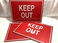 Three new red and white "KEEP OUT" signs stacked and displayed from front showing brand and text.