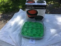 Portable BBQ with Cooler Bag box next to green deviled egg carrier with secure lid