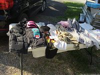 Photo showing an assortment of women's clothing laid out including two black padded coats, socks, and several tops in various colors and patterns.