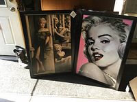 Two large framed Marilyn Monroe pictures displayed side by side on floor with natural lighting.