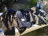 Three jackets laid out on a white table outdoors, two Napa jackets and one plaid insulated coat.