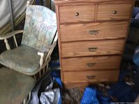 Photo showing the full front view of the pine dresser alongside a cushioned rocking chair and various items on the floor.