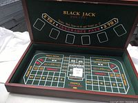 Open wooden box displaying the blackjack game layout on the felt interior surface.