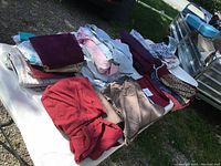 Various used queen size sheets and pillow cases in different colors and some patterns spread out on a table.