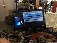 Samsung TV powered on showing channel setup menu displaying interface options and a remote control