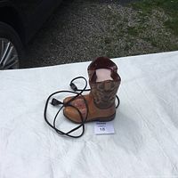 Photo of cowboy boot shaped Scentsy warmer with power cord on white tablecloth.