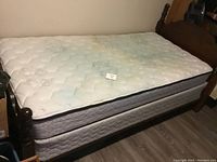 Single bed with dark wood frame and mattress, visible stain on mattress surface.