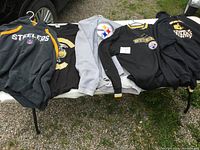 Full view of all 5 Pittsburgh Steelers apparel items including 2 hoodies, 2 sweaters, and 1 T-shirt laid out.
