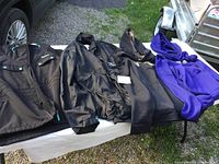 Four men’s jackets displayed on a white surface outdoors, showing variety of styles and sizes.