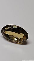 Close-up of oval cut citrine gemstone showing facets and warm golden color.