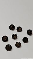 Eight round, calibrated, diamond cut faceted Smokey Quartz gemstones laid out on a white background, showing transparent brown coloration with reflective surfaces.