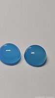 Pair of natural round cabochon icey blue chalcedony gemstones with glossy, translucent surface.