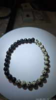 Top view of the stretchy bracelet showing black lava stone beads and cream dalmatian jasper beads with black spots arranged alternately