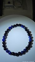 Top down photo showing full circular bracelet layout with alternating black and blue beads