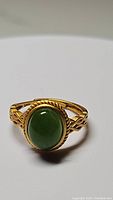 Front view of natural green jade oval cabochon ring set in gold electroplated 925 sterling silver with rope detailing on band
