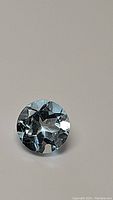 Close-up image of round natural sky blue topaz gemstone showing diamond cut facets and high clarity.