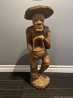 Front view of the large, hand carved wooden pilgrim man sculpture holding a basket and stick.