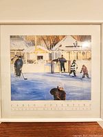 Full view of the framed print showing a winter scene of children playing shinny hockey outdoors in front of snow-covered houses.